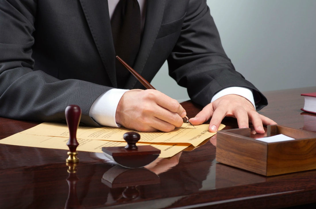 A man in suit and tie writing on paper.